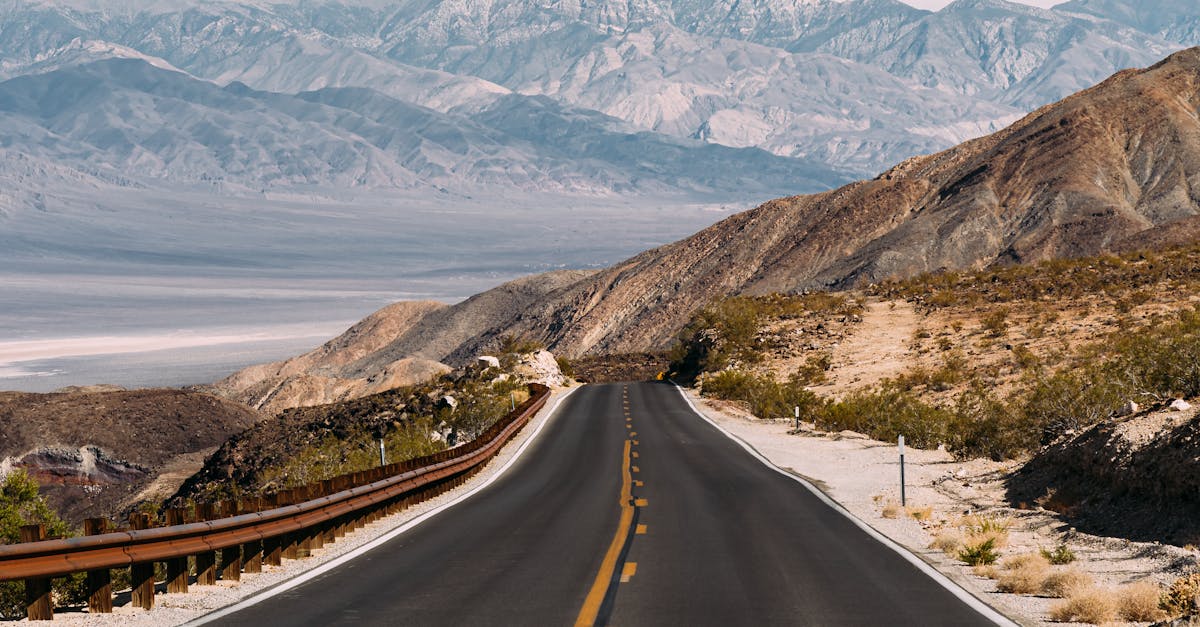 A picturesque highway winding through a desert landscape with distant mountains in the background.